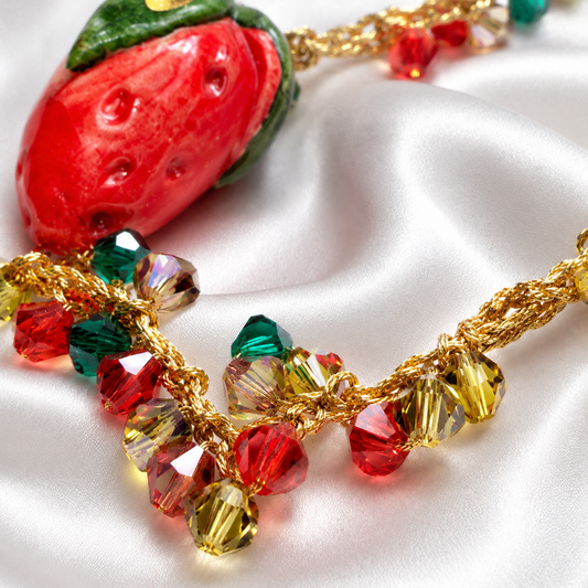Close-up of red green and gold Swarovski crystals with gold crochet details on Sicilian strawberry bracelet
