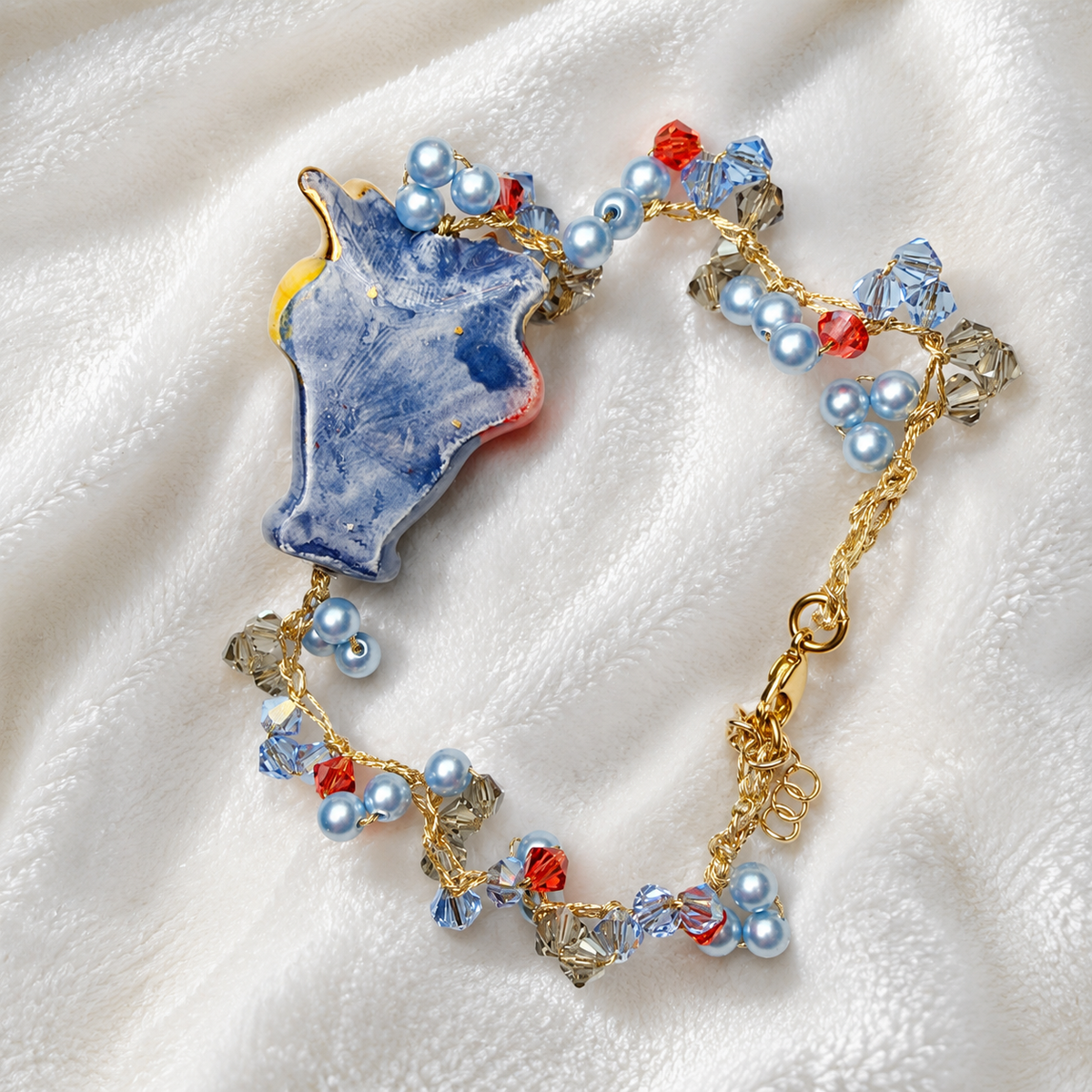 Detail of handcrafted gold-tone bracelet with Swarovski crystals, Majorca pearls and Testa di Moro ceramic charm