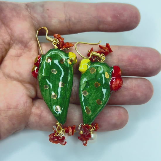 Video showing handmade Sicilian prickly pear earrings in hand-painted Caltagirone ceramic with red coral and freshwater pearls held in hand