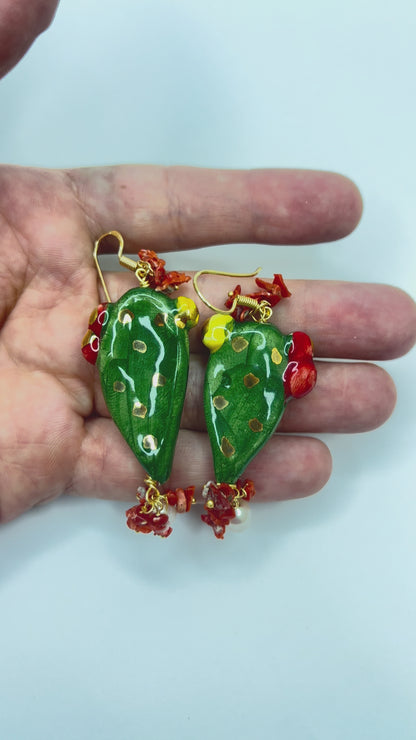Video showing handmade Sicilian prickly pear earrings in hand-painted Caltagirone ceramic with red coral and freshwater pearls held in hand