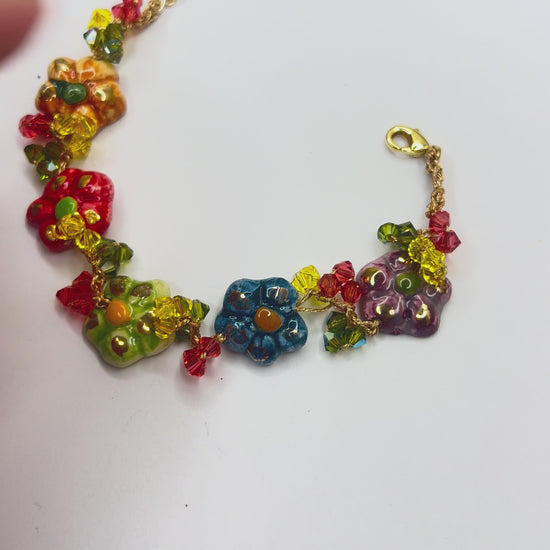 Hand holding handmade Sicilian ceramic flower bracelet crafted in Sicily with colorful floral charms