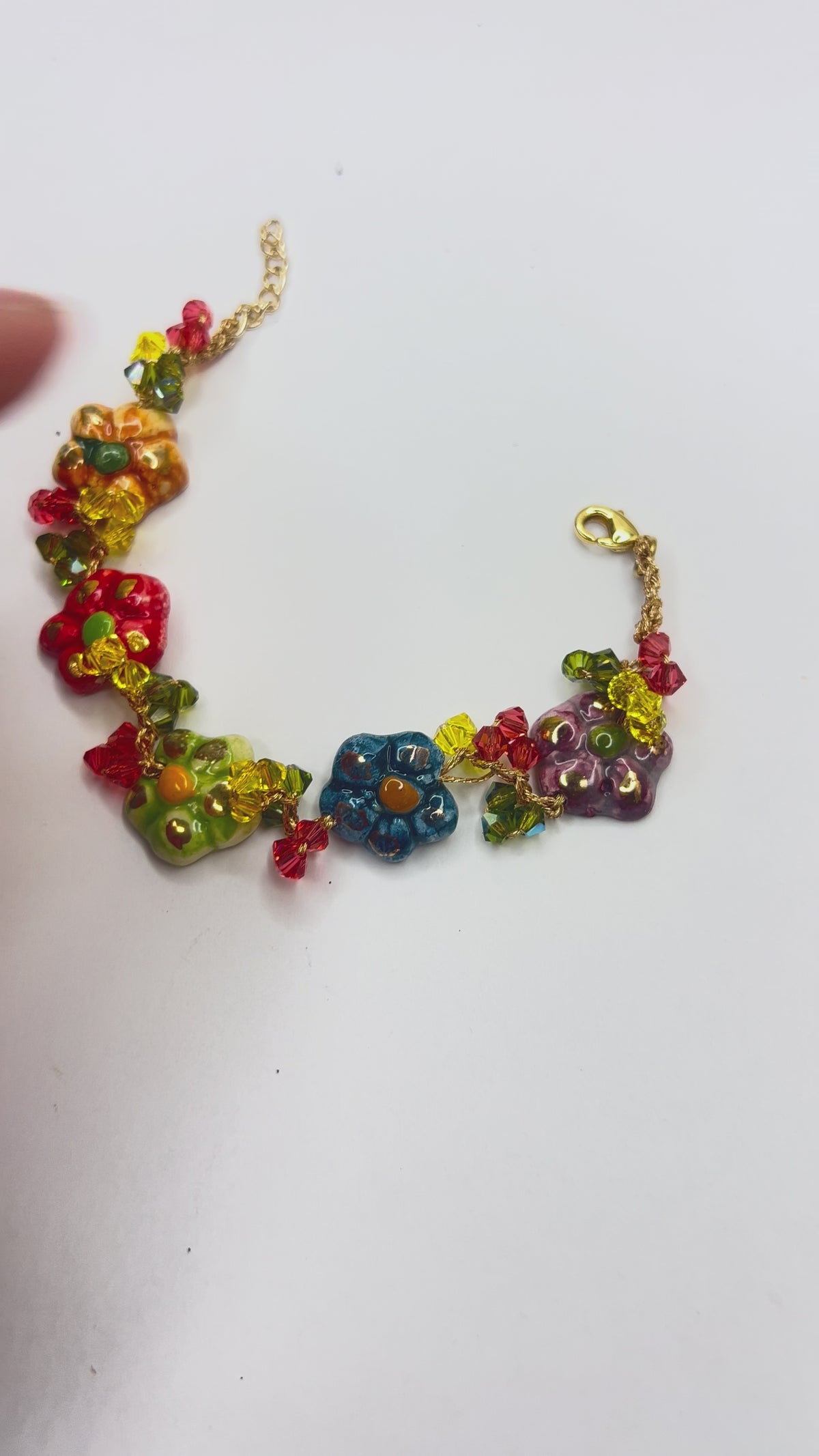 Hand holding handmade Sicilian ceramic flower bracelet crafted in Sicily with colorful floral charms