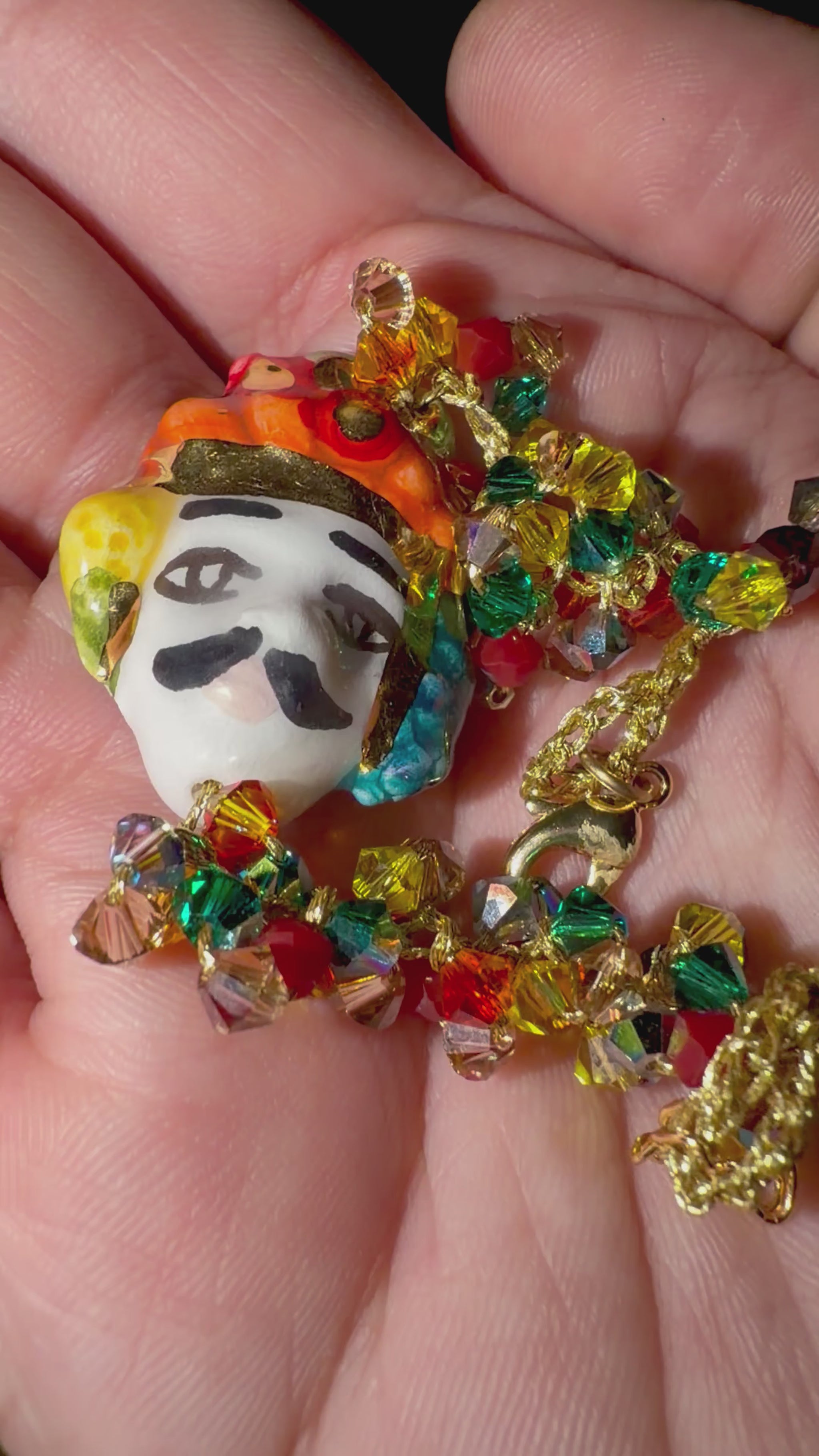 Close-up video of a handmade Sicilian bracelet featuring a hand-painted ceramic Moor’s Head with 15% gold lustre, multicolored Swarovski crystals and a gold-plated brass chain.
