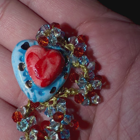 Hand holding handmade Sicilian Sacred Heart bracelet with Caltagirone ceramic and Swarovski crystals