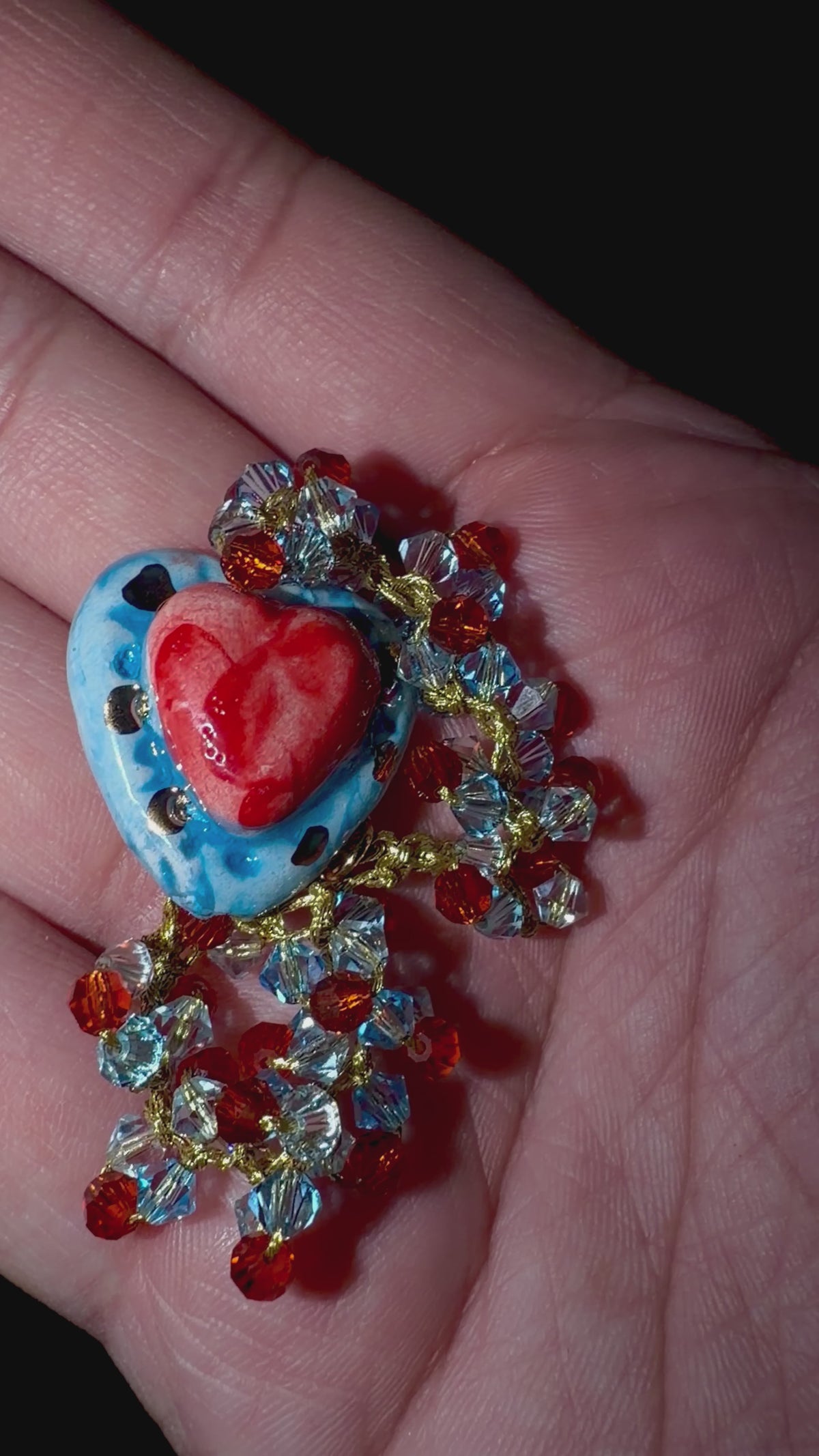 Hand holding handmade Sicilian Sacred Heart bracelet with Caltagirone ceramic and Swarovski crystals