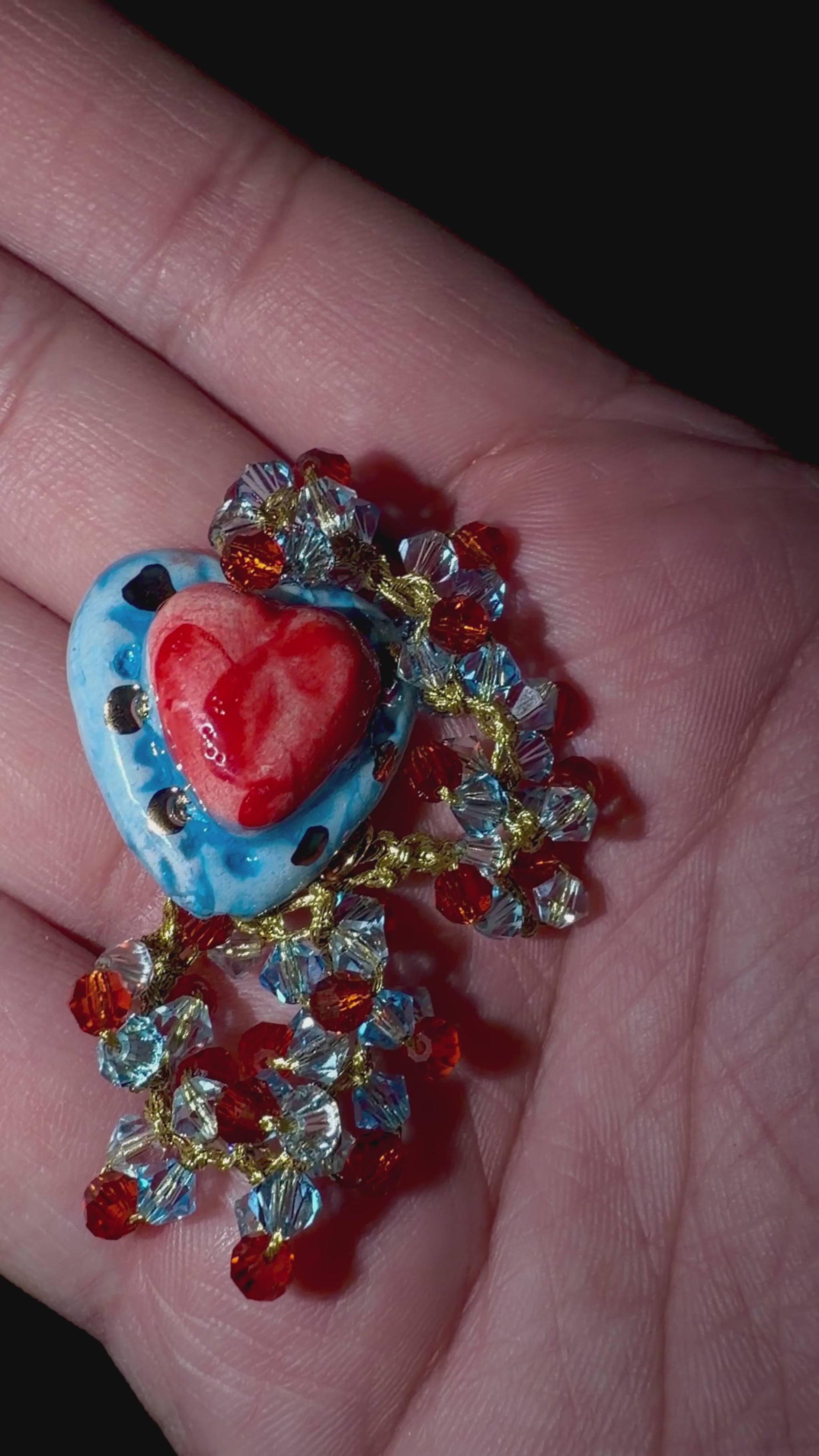 Hand holding handmade Sicilian Sacred Heart bracelet with Caltagirone ceramic and Swarovski crystals