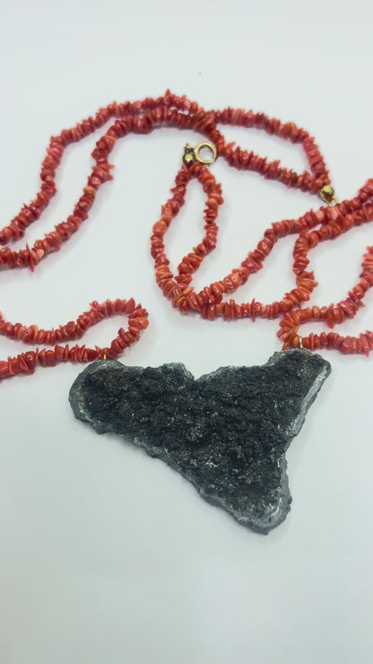 Video close-up of Sicily-shaped Mount Etna lava stone pendant held in hand with Mediterranean red coral necklace