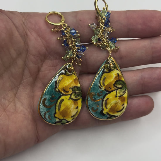 Video showing handmade Mediterranean Dawn Sicilian ceramic drop earrings with lemon motifs and Swarovski crystals held in hand