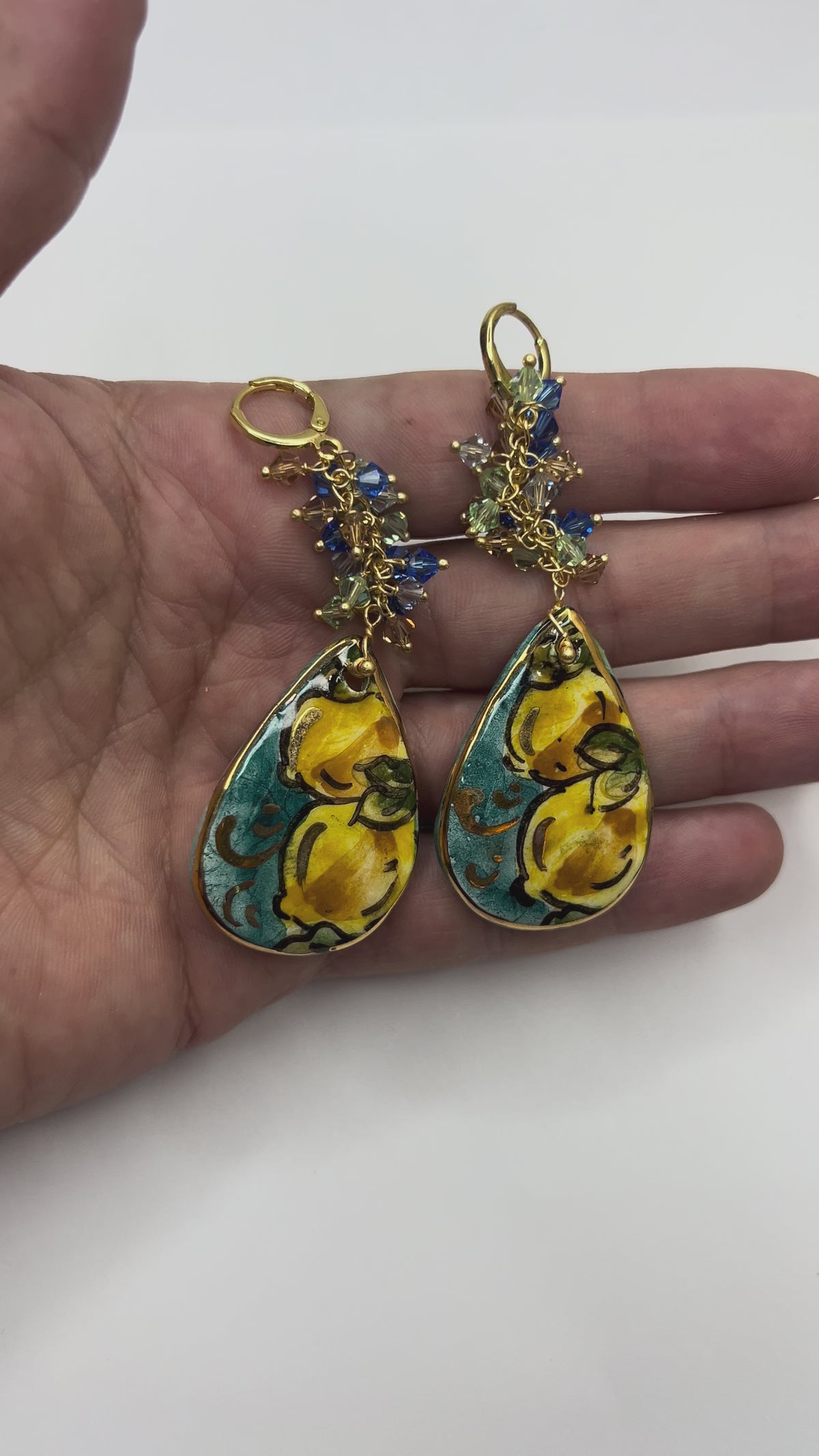 Video showing handmade Mediterranean Dawn Sicilian ceramic drop earrings with lemon motifs and Swarovski crystals held in hand