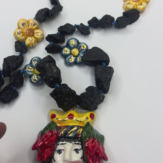 Blue hand-painted Caltagirone ceramic flower surrounded by natural Etna lava stones on Sicilian handmade jewelry